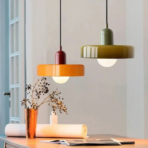 Retro glass pendant lights in vibrant colors hang above a stylishly decorated table in a modern interior space.