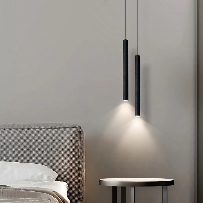 Modern double-head LED pendant light in black, illuminating a minimalist bedroom next to a bed and side table.