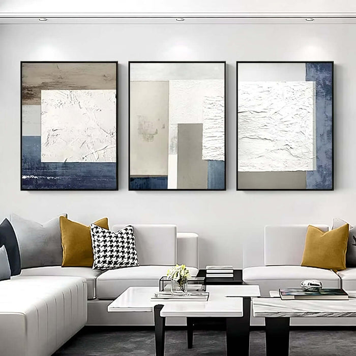 Modern abstract canvas art set with geometric patterns and neutral tones, hung above a contemporary living room sofa.