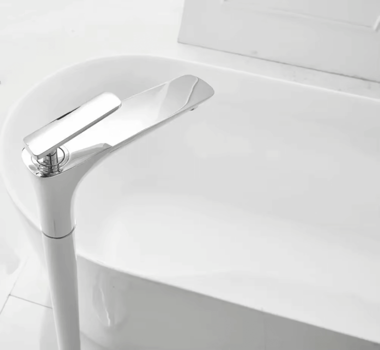 Sleek floor standing bathtub mixer with modern stainless steel design beside a white bathtub.