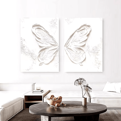 White abstract butterfly oil diptych displayed in a modern living room setting, showcasing minimalist elegance and textured artwork.