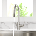 Modern kitchen faucet with swivel spout and chrome finish, featuring a pull-out sprayer, mounted on a marble countertop.