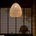 Handwoven bamboo pendant light illuminating a warm, inviting glow in a tranquil Asian-inspired room.